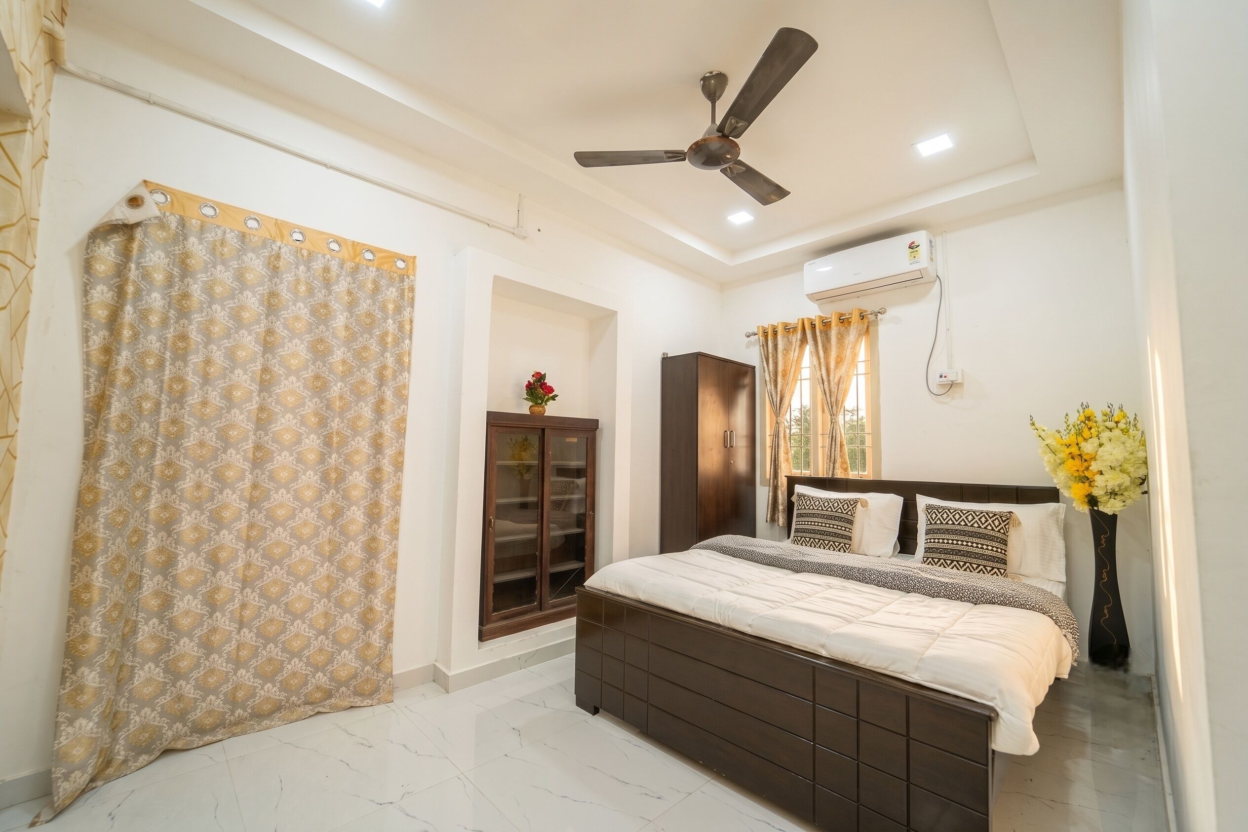 A bedroom with a bed, a wardrobe, a ceiling fan, and an air conditioning unit.