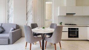 Una cocina moderna con una mesa y sillas, horno empotrado y un sofá gris.