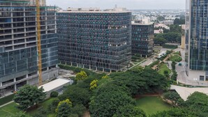 Un edificio de gran altura con varios pisos, rodeado de vegetación exuberante y un jardín bien cuidado.