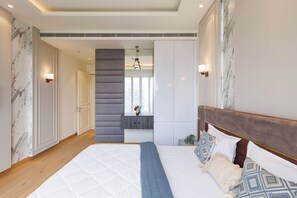 Ein modernes Schlafzimmer mit einem großen Bett, einer grauen Akzentwand und Blick auf die Stadt durch ein Fenster.