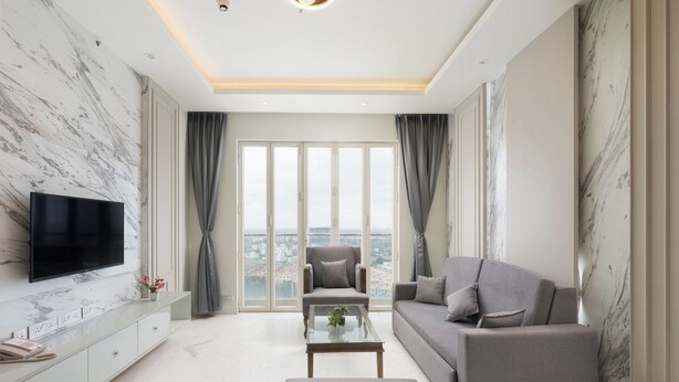 Una sala de estar moderna con una televisión de pantalla plana, un sofá, un sillón y una mesa de centro.