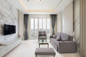 Una sala de estar moderna con una televisión de pantalla plana, un sofá, un sillón y una mesa de centro.