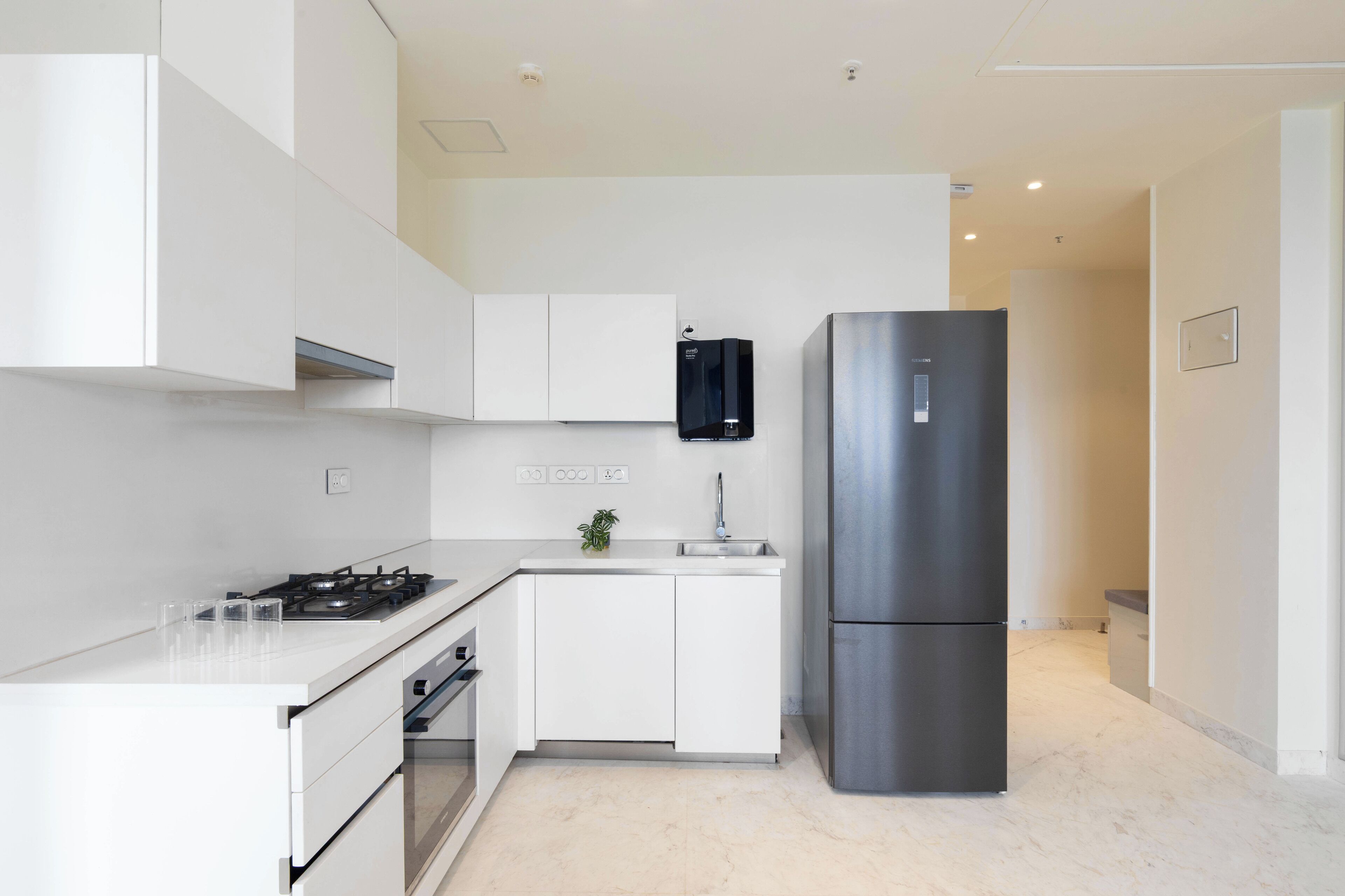 A modern kitchen with white cabinetry, a stainless steel refrigerator, and a gas stove.