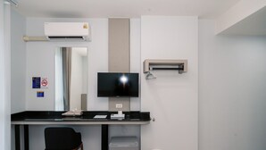 A modern office space with a desk, chair, television, air conditioning unit, and a trash bin. - One Budget Hotel Chiangrai Maesai Payang (Mae Sai)