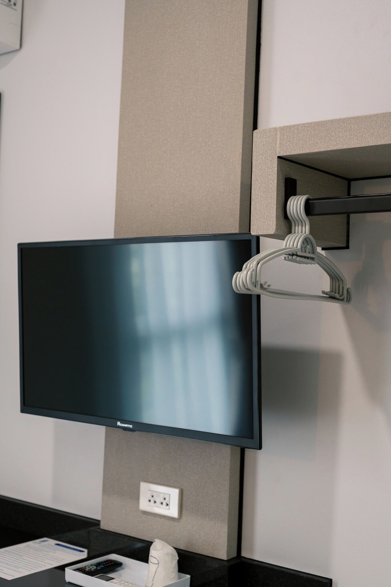 Una habitación de hotel moderna con un televisor de pantalla plana montado en la pared, una encimera negra y un dispensador de pañuelos blancos.