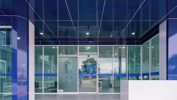 A modern building entrance with glass doors, a welcome sign, and a security camera above the door. - One Budget Hotel Chiangrai Maesai Payang (Mae Sai)