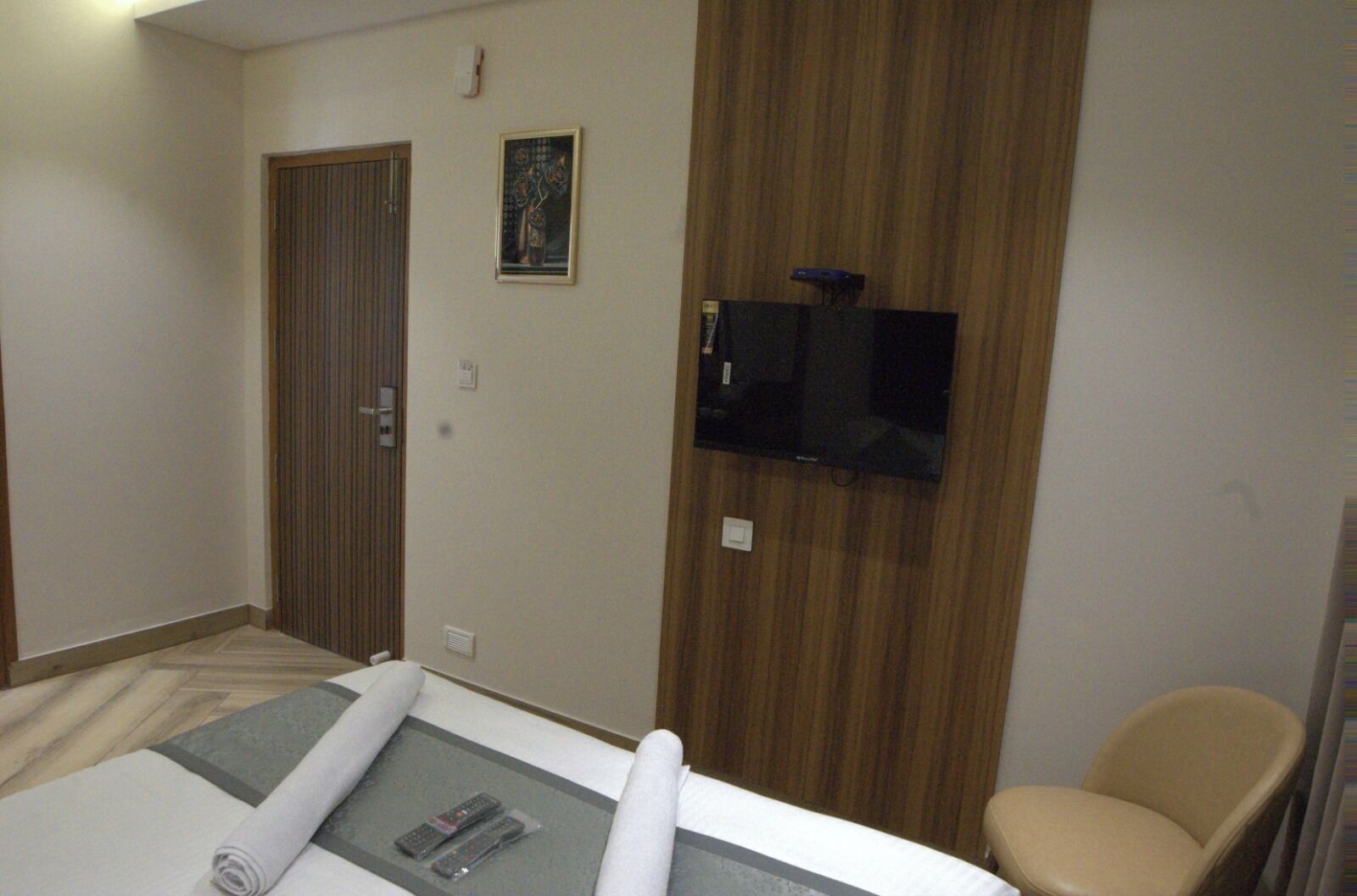 Una habitación de hotel con una cama, un televisor en la pared, una silla y una puerta.