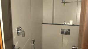 A compact bathroom with a toilet, bidet, and shower. - Grand Sea Way (Chennai)