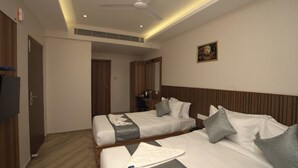 A hotel room with two beds, a ceiling fan, a television, and a painting on the wall. - Grand Sea Way (Chennai)