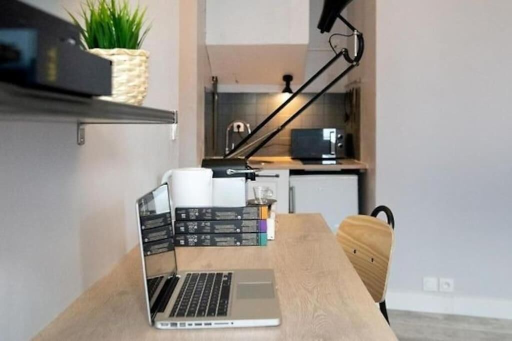 A modern kitchen with a laptop on a wooden table, a plant, and a black lamp.