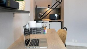 Una cucina moderna con un laptop su un tavolo di legno, una pianta e una lampada nera.