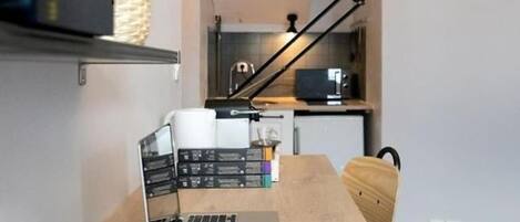 A modern kitchen with a laptop on a wooden table, a plant, and a black lamp.
