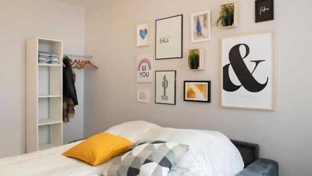 Una camera da letto con un letto, un armadio e una parete decorata con quadri e una grande insegna con una lettera.