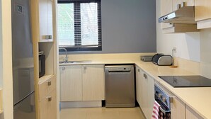A modern kitchen with a stainless steel refrigerator, a dishwasher, and a built-in oven. - La Residence with LOV (Cap Malheureux)