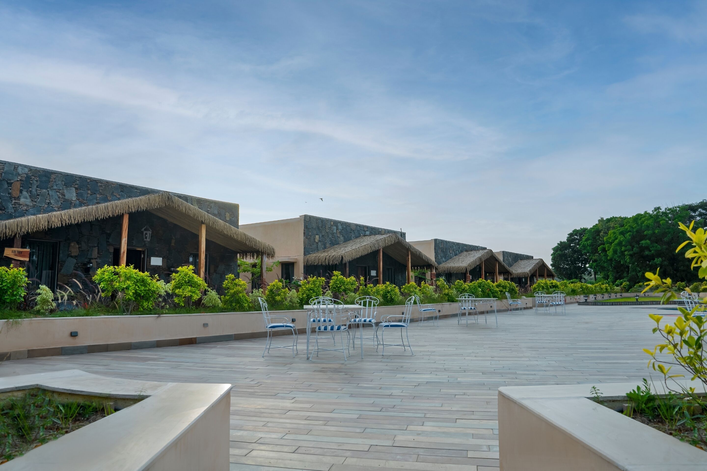 A resort with thatched-roof buildings, outdoor seating, and a paved walkway.