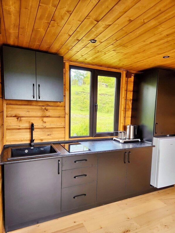 A modern kitchen with wooden ceiling and walls, a large window, and stainless steel appliances.