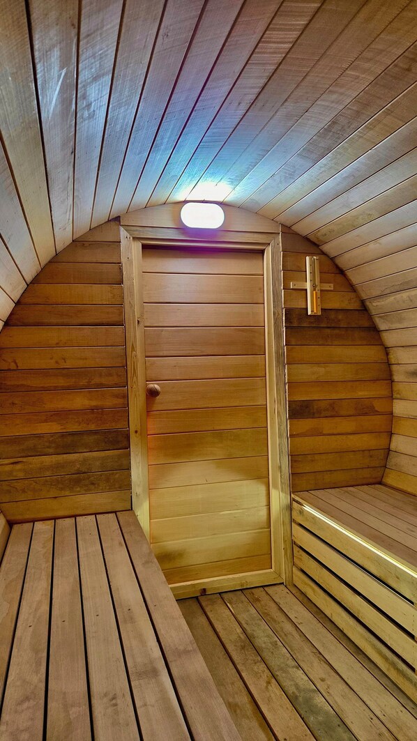 A sauna with wooden walls and a sloped ceiling.