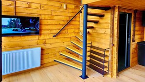 Ein Holzinnenraum mit Treppe, einem an der Wand befestigten Fernseher und einer Heizung.