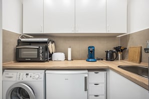 Una cocina equipada con microondas, tostadora, cafetera y lavavajillas.