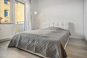 Un dormitori amb un llit, una finestra i un radiador.