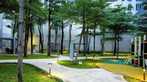 A landscaped outdoor area with pathways, trees, and a playground. - Premium Taman Anggrek Residences (West Jakarta)