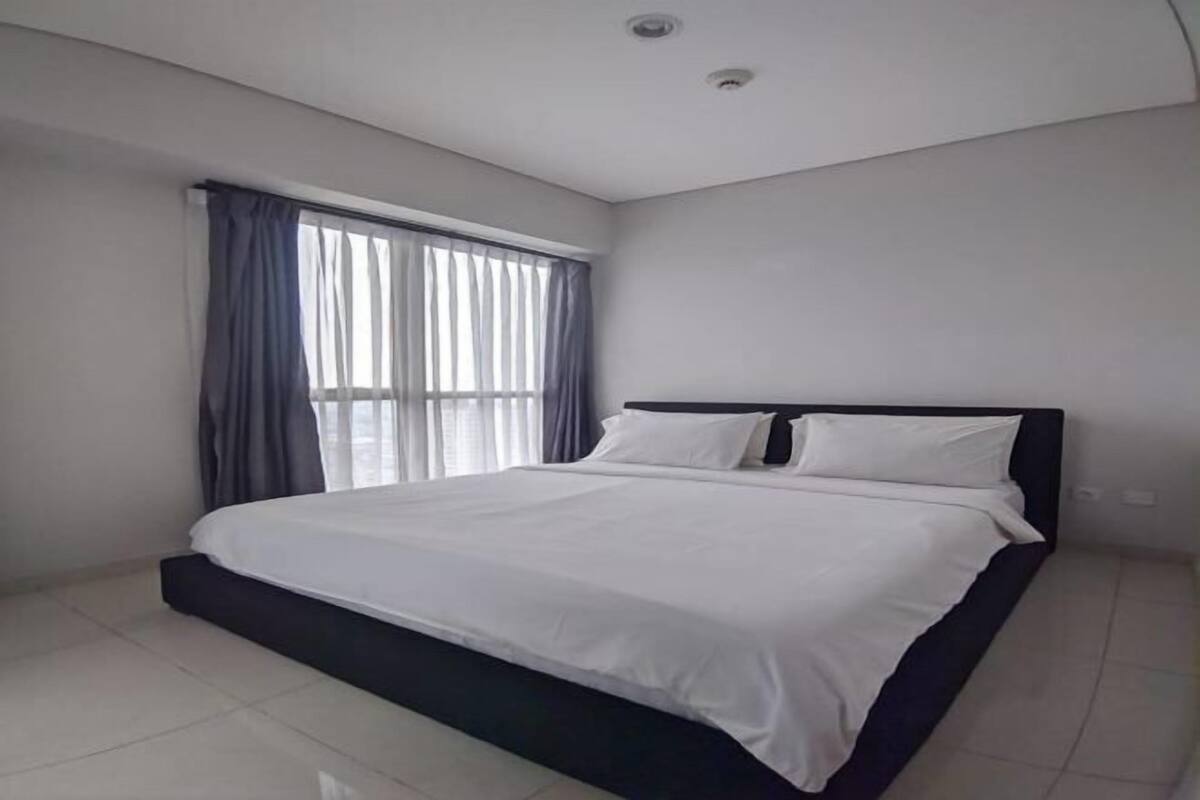 A bedroom with a bed, curtains, and a window.