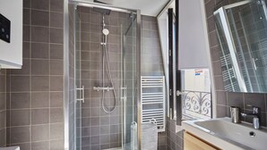 Ein modernes Badezimmer mit einer Duschkabine, einem integrierten Waschbecken und einem großen Spiegel.