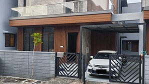 A modern two-story house with a balcony, a car parked in the driveway, and a gated entrance. - 2D-Villastay (Kovalam)