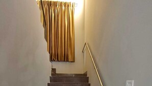 A staircase with a handrail, a light switch, and a curtain. - 2D-Villastay (Kovalam)