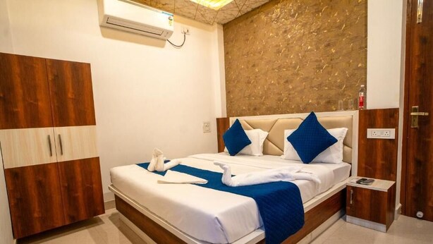 Una camera d'albergo moderna con un armadio in legno, un letto con biancheria azzurra e bianca e un comodino.