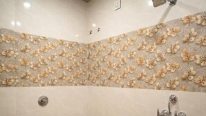 Un bagno con il water, una doccia e un secchio rosso.