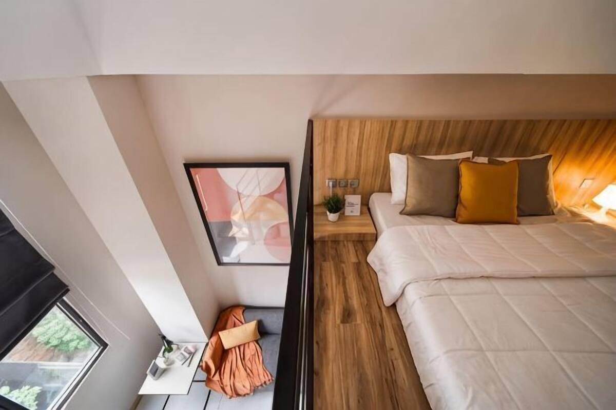 A modern hotel room with a bed, bedside table, and a window.