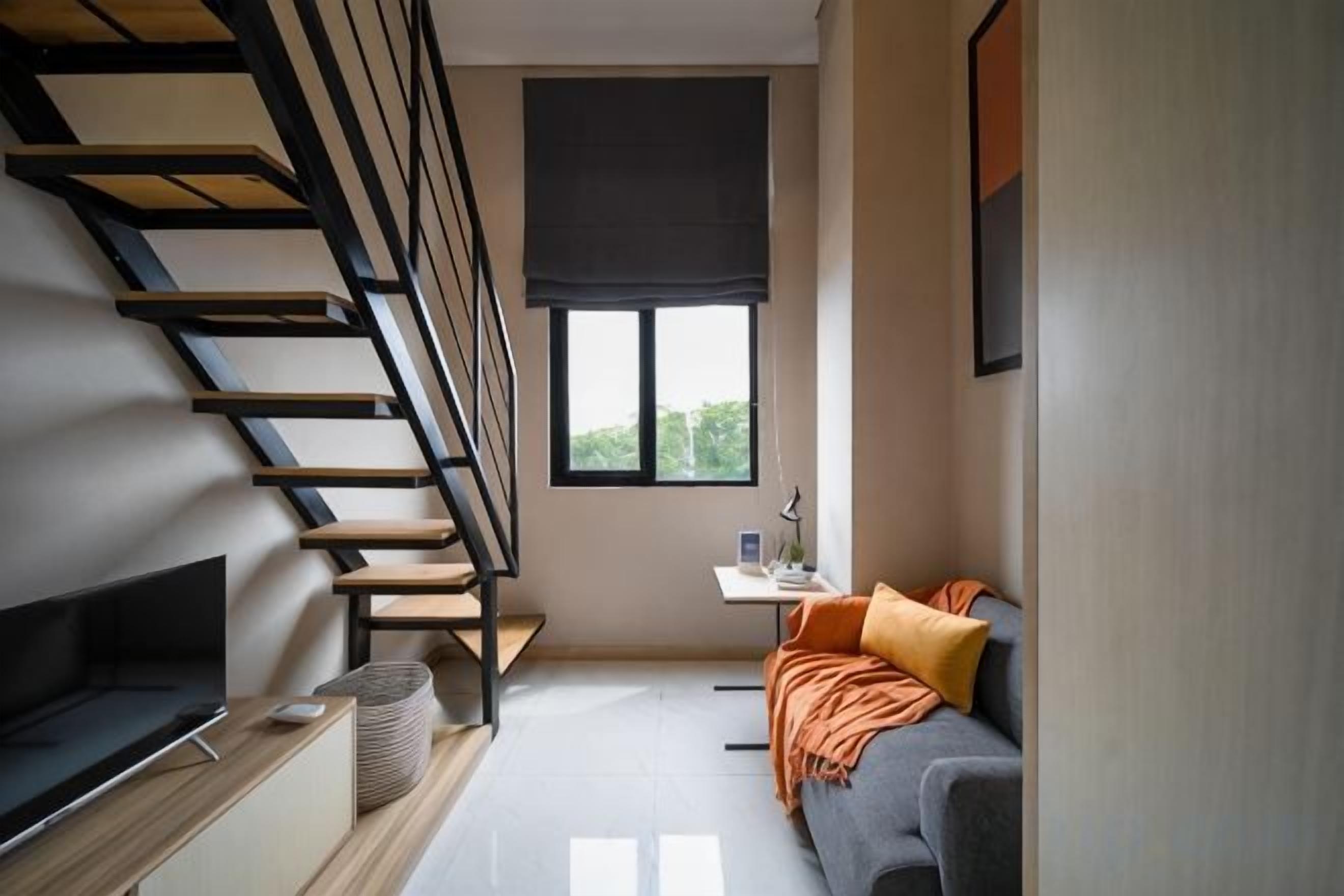 A modern interior with a staircase, a flat-screen TV, a sofa, and a small table.