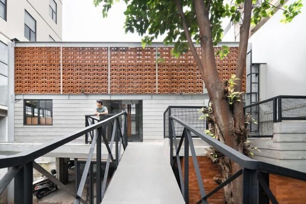 Un edificio moderno con fachada de madera, una escalera de metal y un árbol.