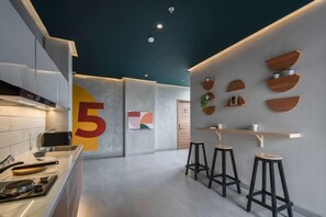 Une cuisine moderne avec un grand chiffre « 5 » peint sur le mur, un coin bar avec des tabourets et un design minimaliste.