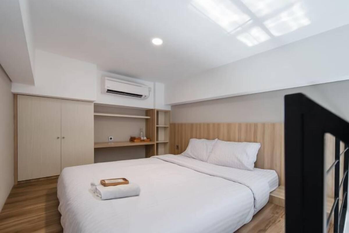 A modern bedroom with a bed, built-in wardrobe, and shelves.
