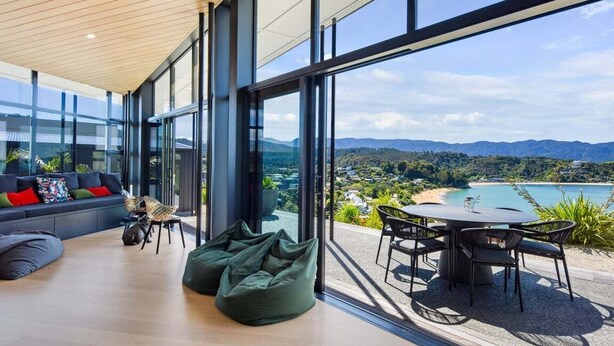 Ein modernes Interieur mit einer großen Glaswand, die einen schönen Blick auf Strand und Berge bietet.
