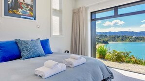 Ein Schlafzimmer mit einem großen Bett, Seeblick und einem Berg in der Ferne.