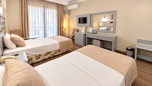 Une chambre d’hôtel avec deux lits, un bureau, une chaise, une télévision et une fenêtre avec des rideaux.