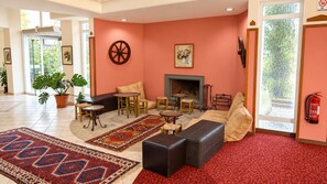 A spacious living area with a fireplace, comfortable seating, and a large window providing a view of greenery.