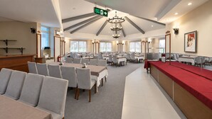Un vaste espace dédié à la restauration, avec de nombreuses tables et chaises, un comptoir d’accueil et un lustre.