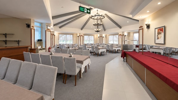 A spacious dining area with multiple tables and chairs, a reception desk, and a chandelier. - VILLA LYCUS TERMAL OTEL (Denizli)