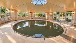 Une piscine intérieure dotée d’un toit en verre, d’un espace détente et d’un affichage de la température.