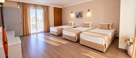 A hotel room with a wooden floor, two beds, a wardrobe, a desk, and a lamp.