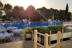 Una piscina techada, una piscina al aire libre, sombrillas