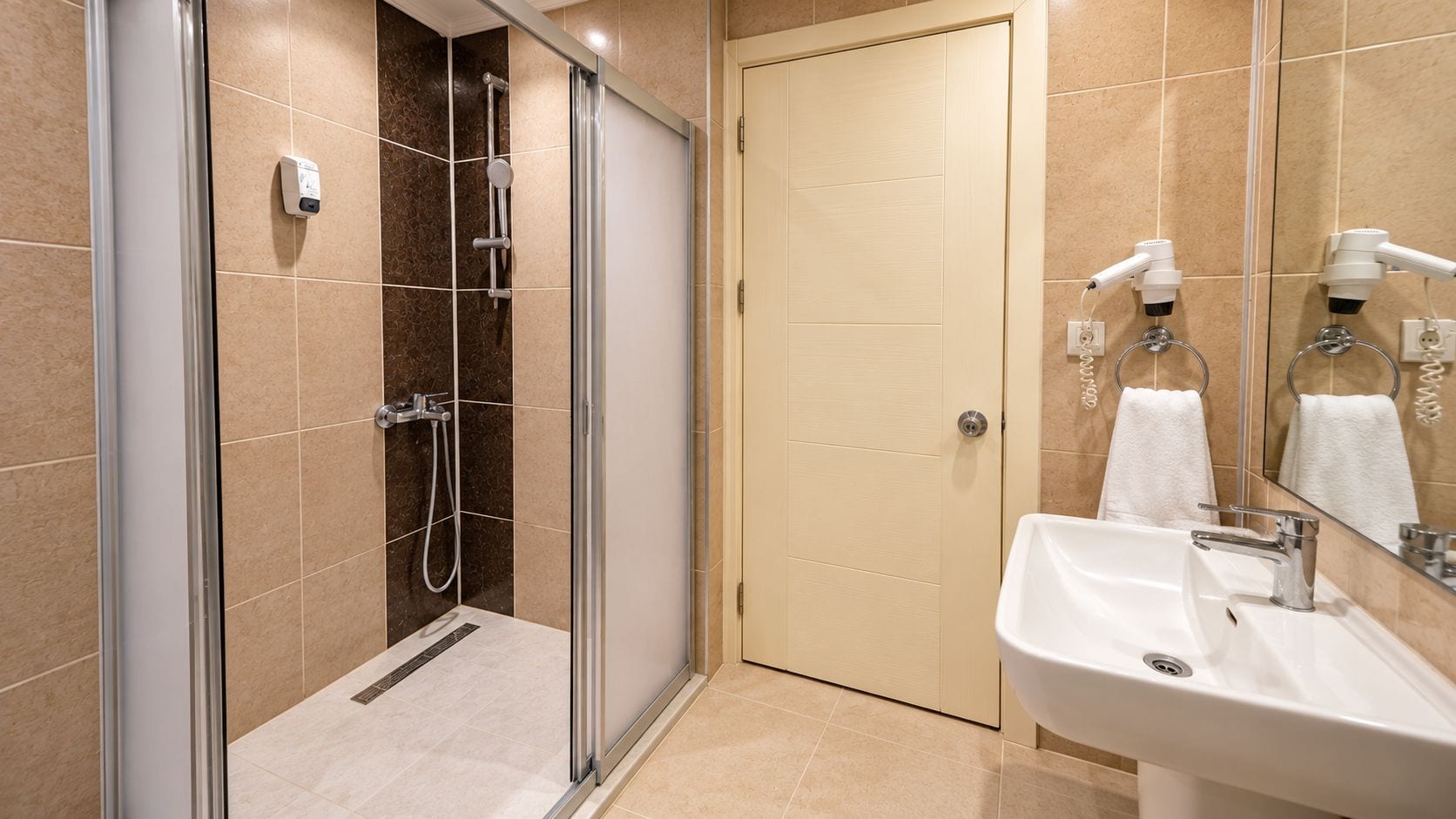Un baño con ducha de vidrio, lavamanos con espejo y perchero para toallas.