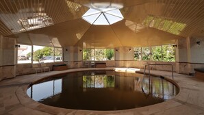 An indoor swimming pool with a high ceiling and skylight, surrounded by stone walls and windows. - VILLA LYCUS TERMAL OTEL (Denizli)