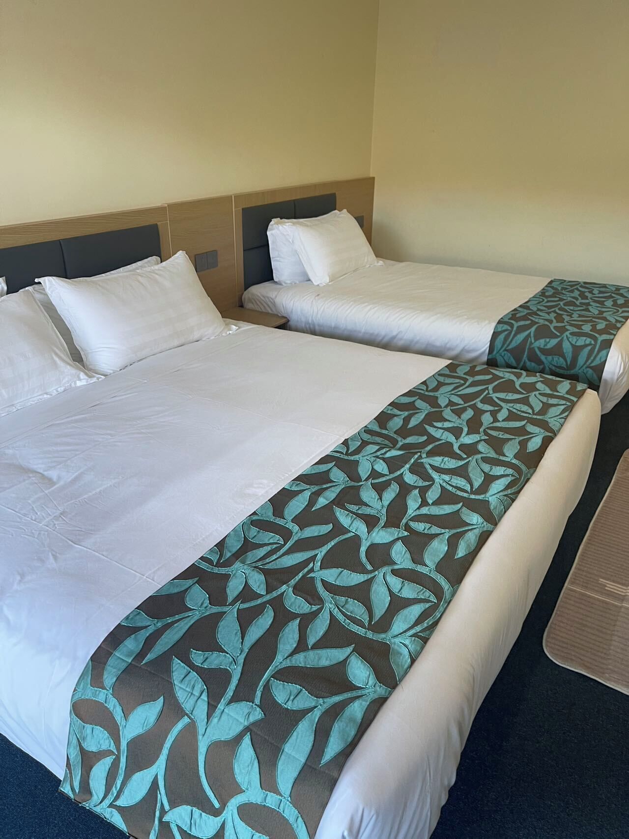 A hotel room with two single beds, each with white linens and a headboard.