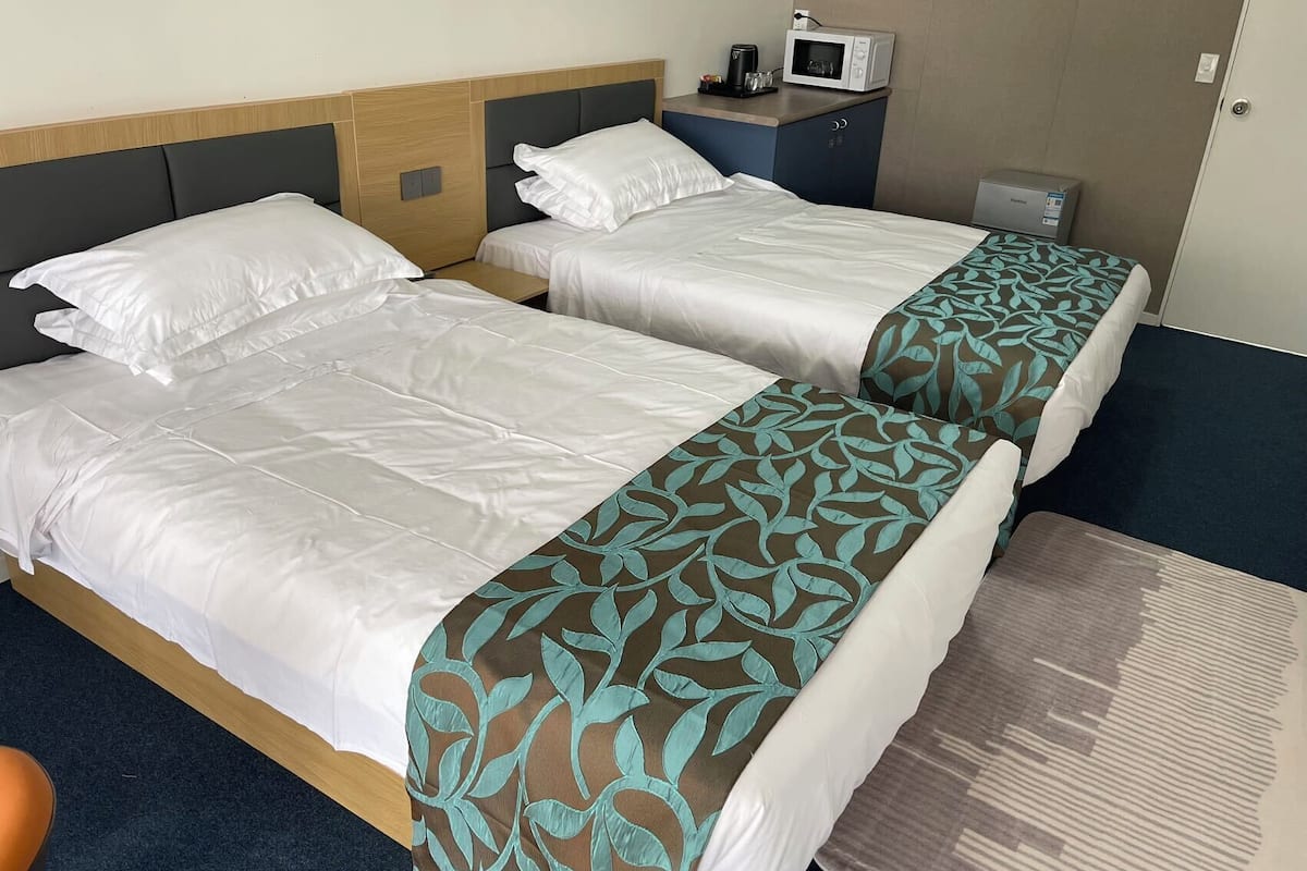 A hotel room with two beds, a microwave, a coffee maker, and a small table.