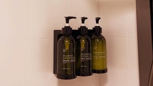 Ein Duschbereich mit Handbrause und drei Flaschen Shampoo, Duschgel und Conditioner.